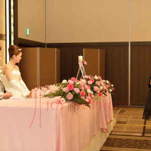 披露宴で来賓のスピーチを聞く新郎と新婦